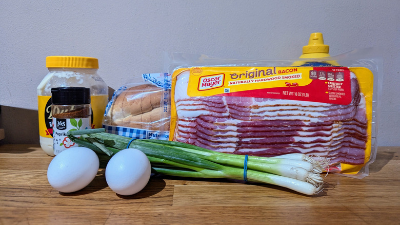 Various ingredients for bacon egg salad sandwich on kitchen island.