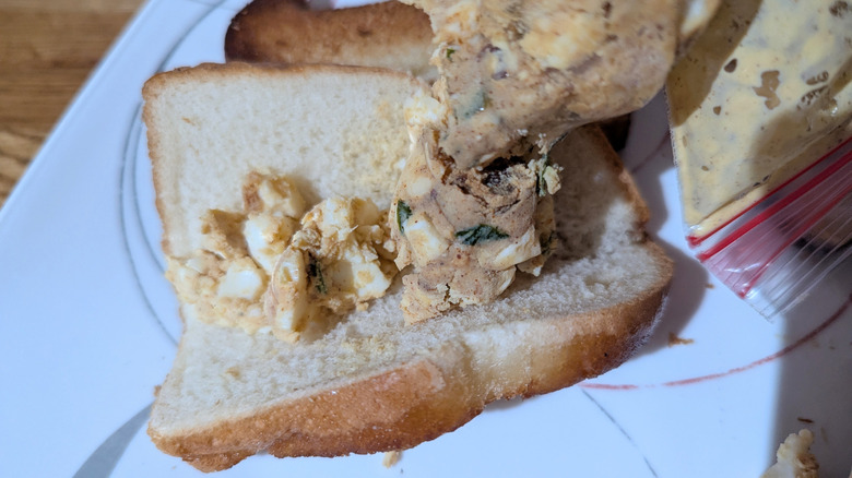 Bag roughly piping coarse egg salad into a folded piece of fried bread.