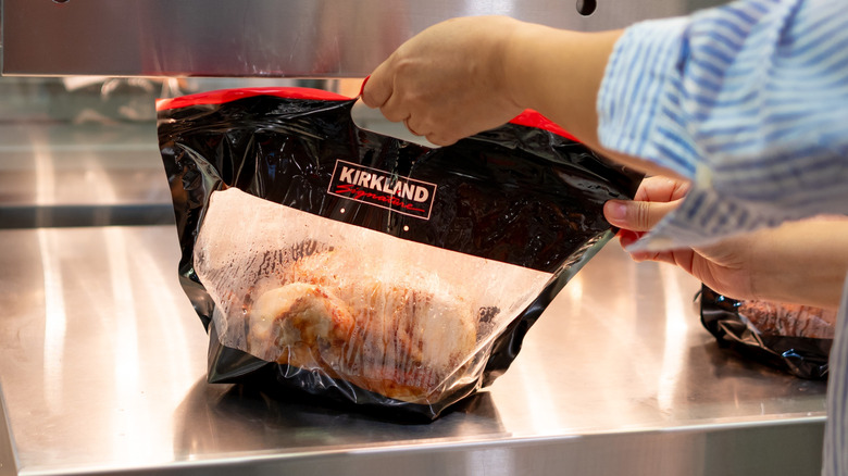 person grabbing Kirkland rotisserie chicken