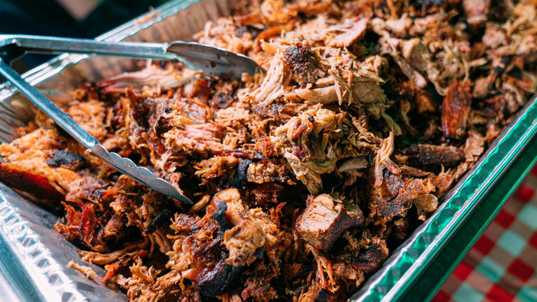 Shredded seasoned meat in an aluminum pan