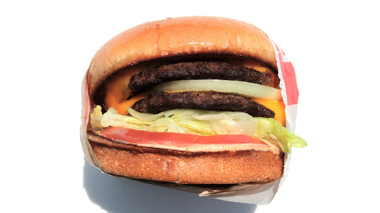 A closeup of In-N-Out burger with onion, patty and cheese on a white background
