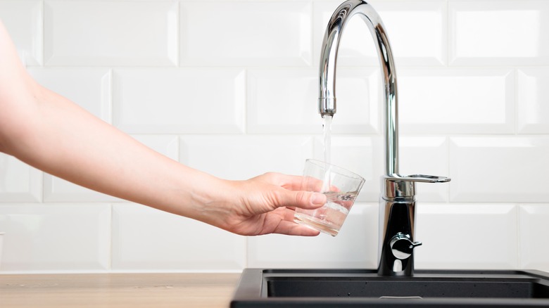 hand of someone filling a glass with water from a tap