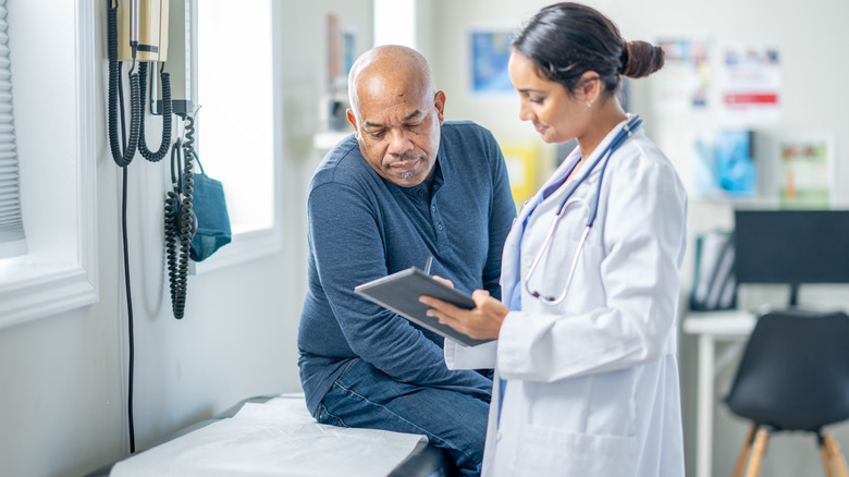 patient on exam table looking at a tablet with a doctor