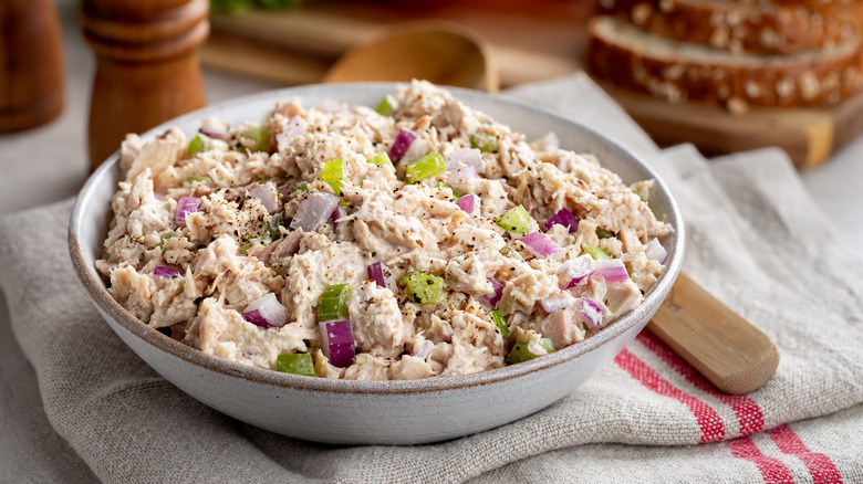 A bowl of tuna salad with celery and onions on a cloth