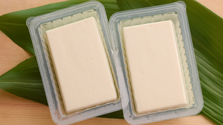 Top view of open plastic packages of blocks of tofu in water