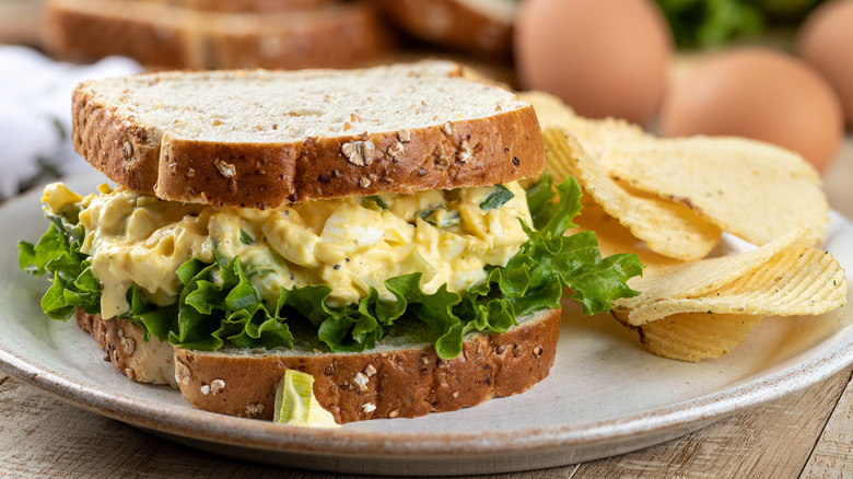 egg salad sandwich on plate with potato chips