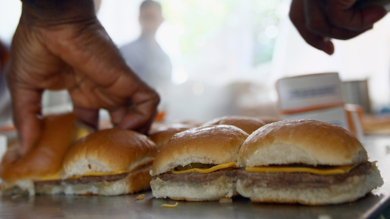 A white castle employee assembling burgers