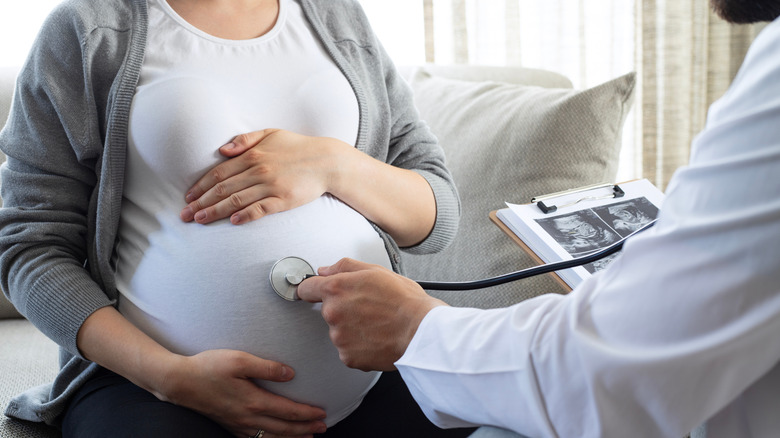 A doctor examining a pregnant patient with a stethoscope