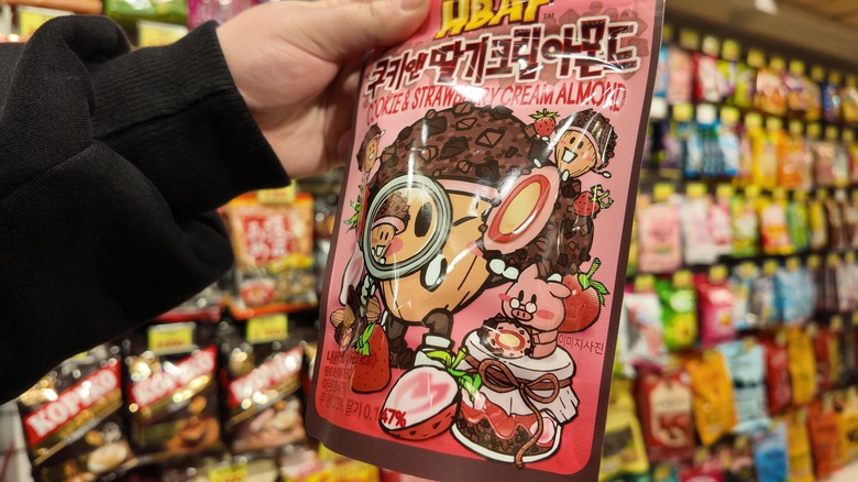 A hand holding a Korean cookie in a supermarket aisle