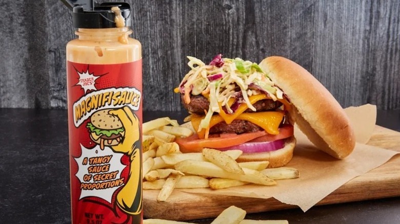 bottle of Trader Joe's Magnifisauce in front of a two-patty cheeseburger and a pile of french fries