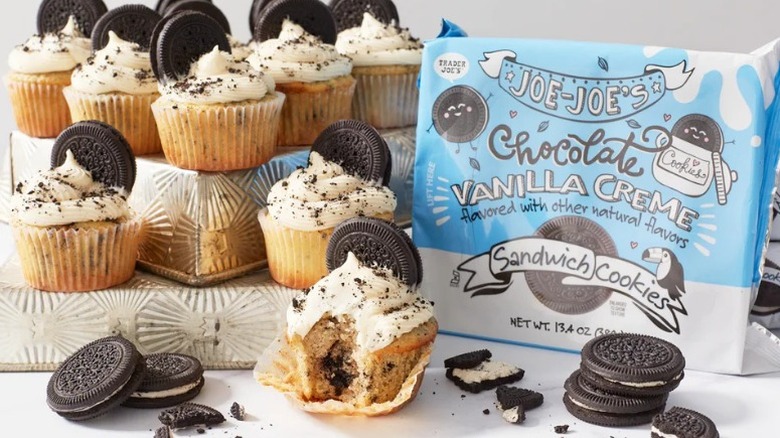 package of Chocolate Vanilla Creme Joe-Joe's with a pile of frosted, cookie-garnished cupcakes