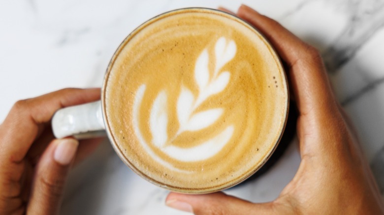 Top view of hands holding a latte