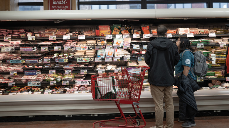 Trader Joe's refrigerated section with various products and two customers standing in front.
