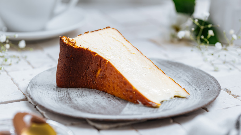 Slice of Basque cheesecake on plate on table with decorations.