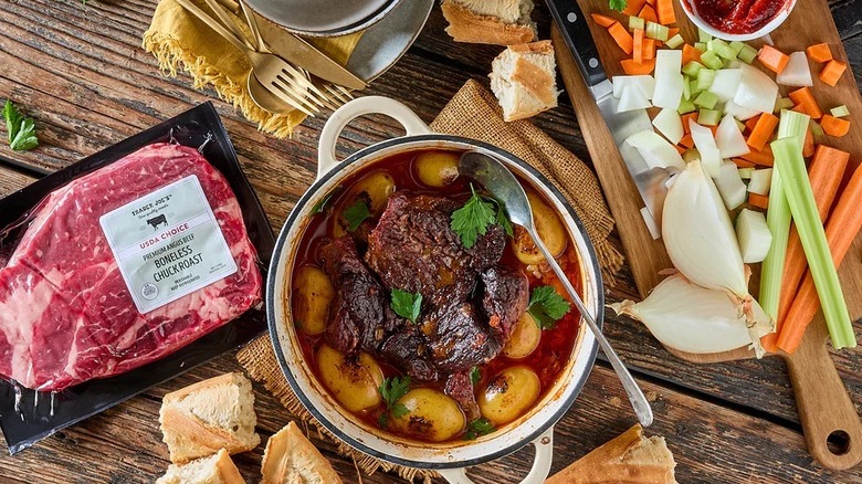 Package of Trader's Joe's chuck roast next to a pot roast, chunks of bread, and assorted raw vegetables