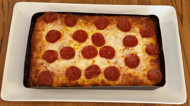 A rectangular pizza with pepperoni on a white serving platter.