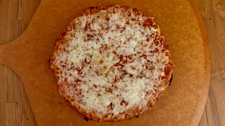 A plain red sauce pizza on a pizza peel.