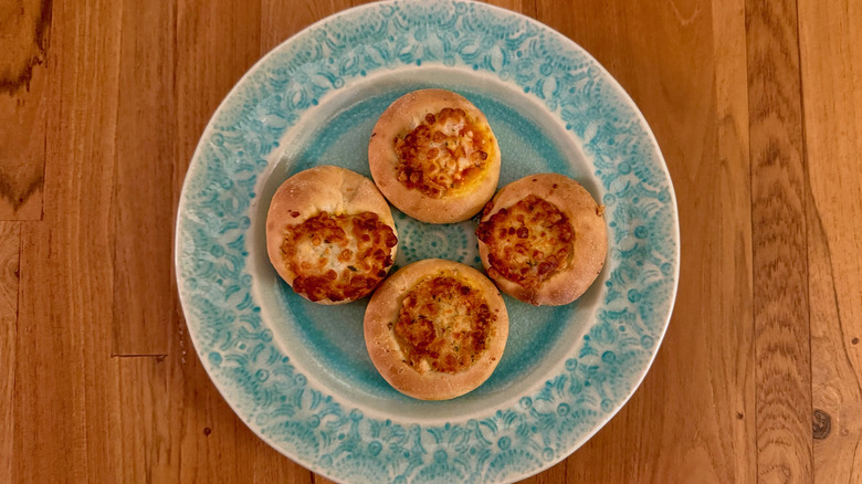 Four small cheese pizzas on a blue plate on a wooden table.