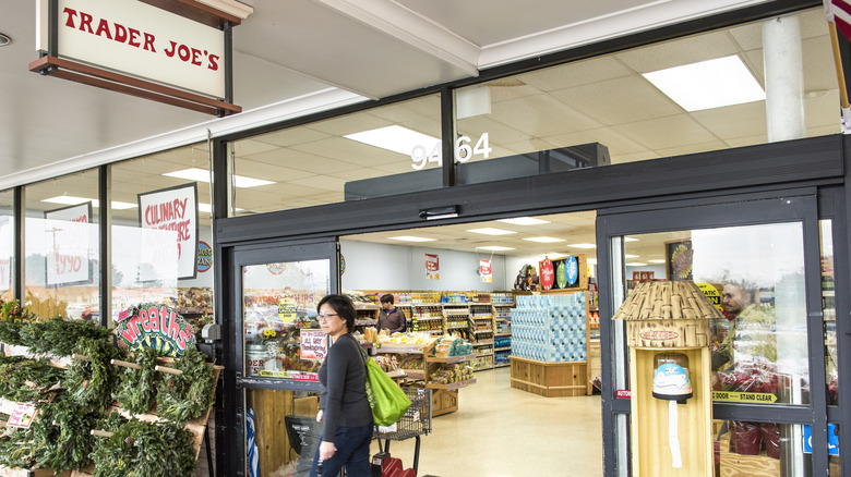 The entrance of a Trader Joe's location as a shopper is walking out of it.