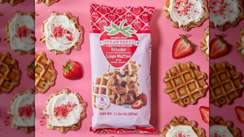 A pink bag of Trader Joe's Strawberry Brioche Style Liège Waffles beside strawberries and waffles on a pink background