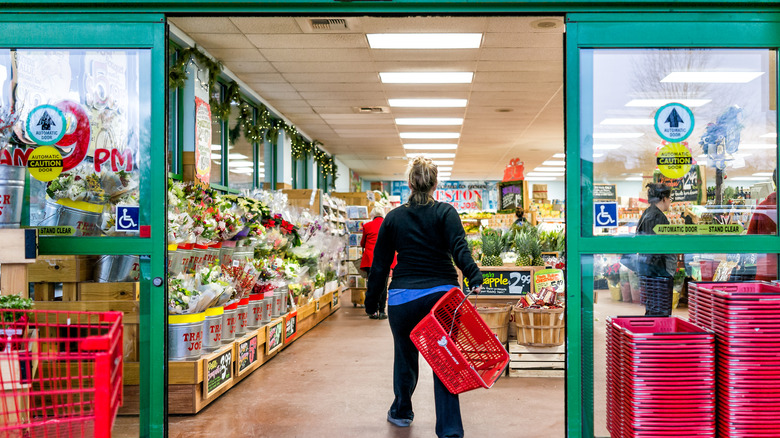 Customer with red shopping basket walking into Trader Joe's