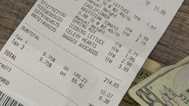 close up of a receipt next to $20 bill on wooden table