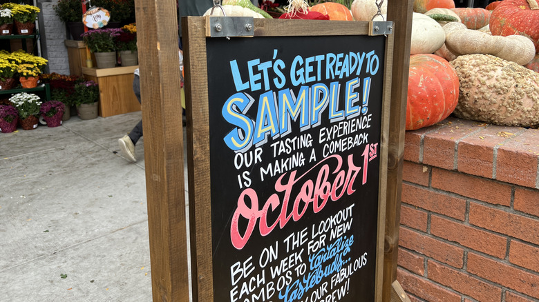 Sign about samples outside Trader Joe's with pumpkins and gourds in background