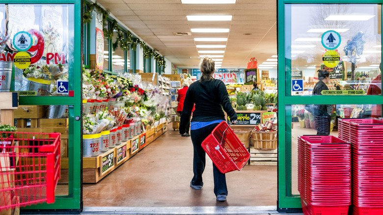 A shopper carrying a basket entering a Trader Joe's store