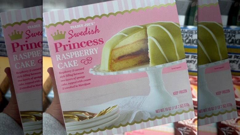 Person holding Trader Joe's Swedish Princess Raspberry Cake box in store.