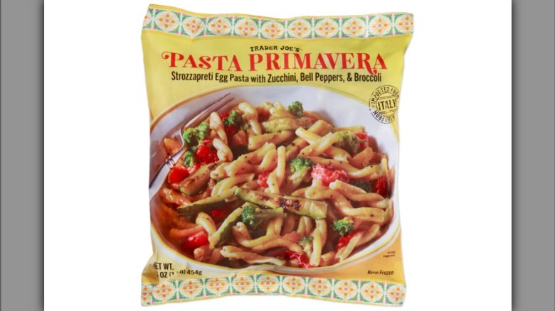 Pasta in a bowl tossed with parmesan with a fork and spoon.
