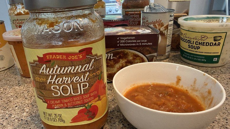 Jar of Trader Joe's Autumnal Harvest Soup next to some in a white bowl with other TJ's soups in background