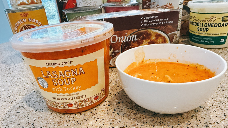 Trader Joe's Lasagna Soup next to some in a white bowl with other TJ's soups in background