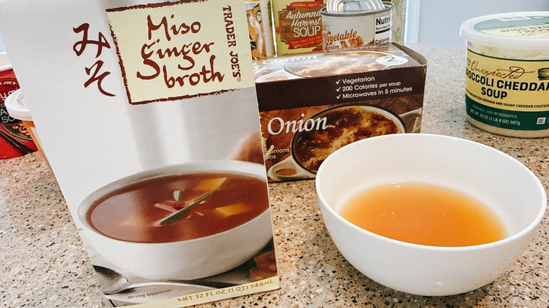Trader Joe's Miso Ginger Broth next to some in a white bowl with other TJ's soups in background