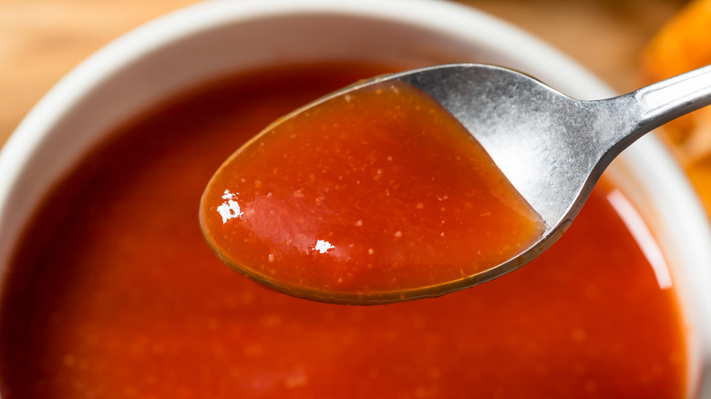 A spoon dipping into a bowl of homemade barbecue sauce