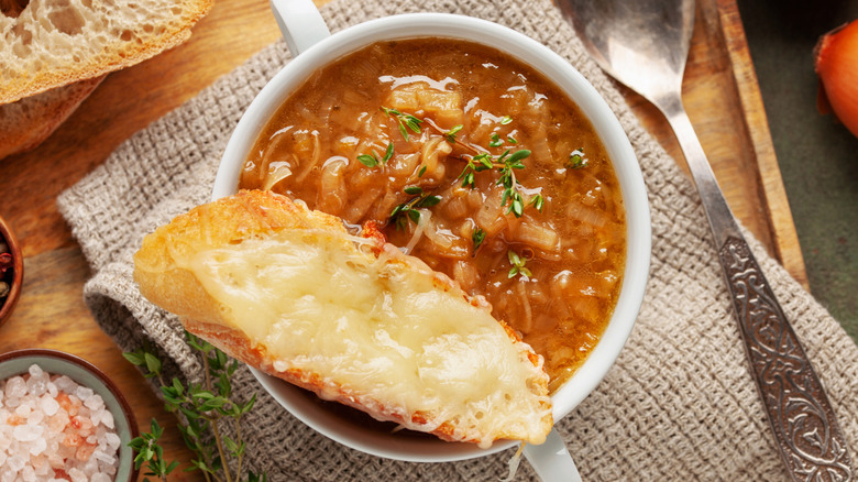 Top view of bowl of French onion soup with piece of cheesy toasted bread