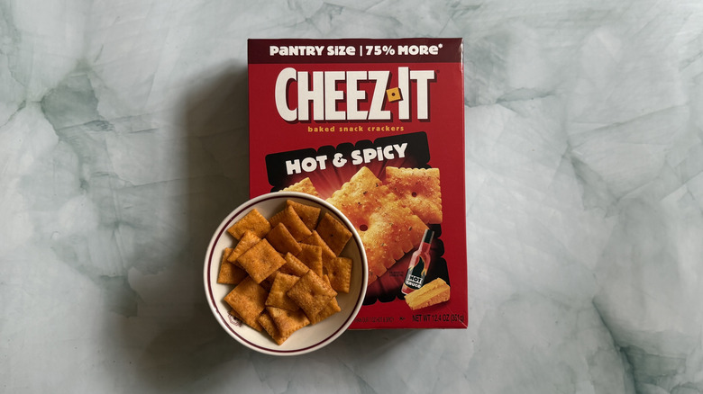 Box of Cheez-It Hot & Spicy Snack Crackers laid down under bowl of the Cheez-Its