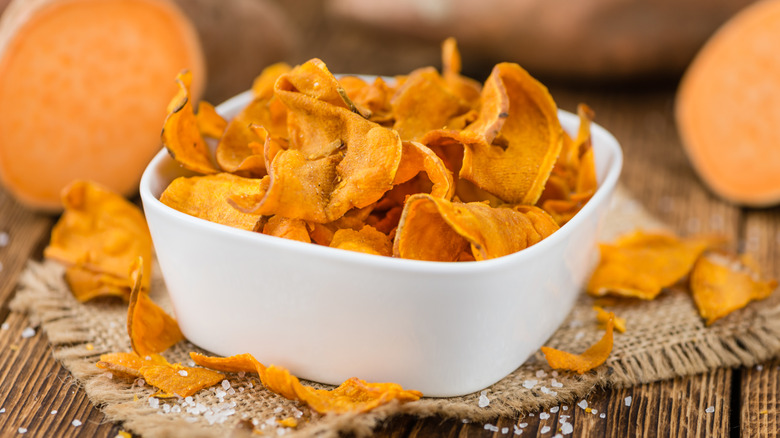 Sweet potato chips in a bowl with fresh sweet potatoes