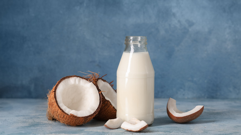 A fresh bottle of coconut milk next to an open coconut