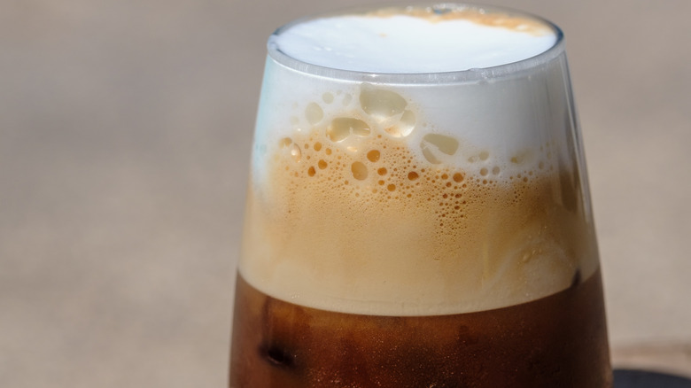 Cold foam tops an iced coffee in a glass