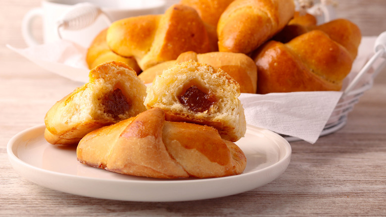 A bowl and plate of homemade crescent rolls filled with jam