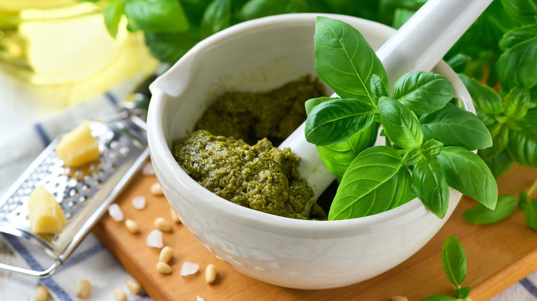 Green pesto in a white bowl with a basil sprig
