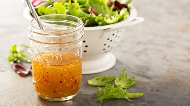 Vinaigrette in a mason jar with salad in the background