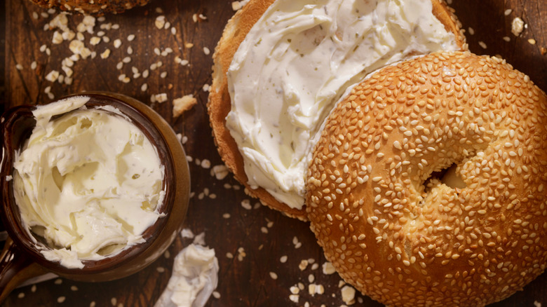 A bowl of cream cheese spread on a bagel with a knife