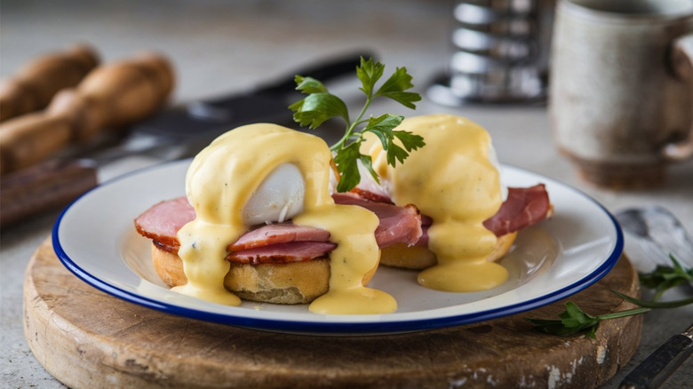 Two eggs Benedict on a white plate, garnished with parsley