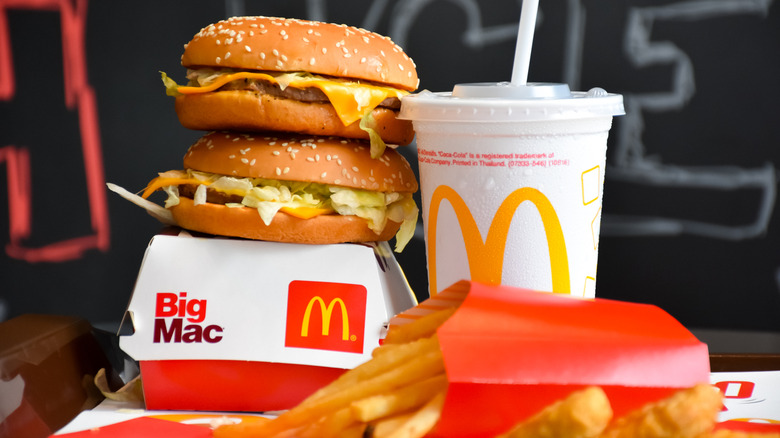 Two McDonald's cheeseburgers stacked on top of a big mac box with fries and a drink