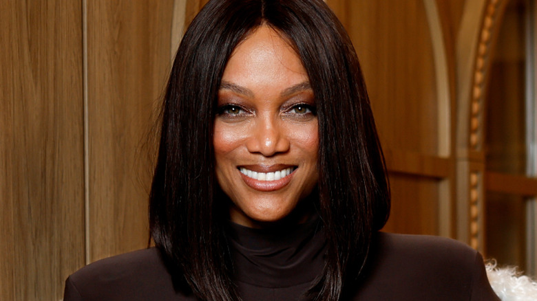 Tyra Banks smiles in a brown top at an event
