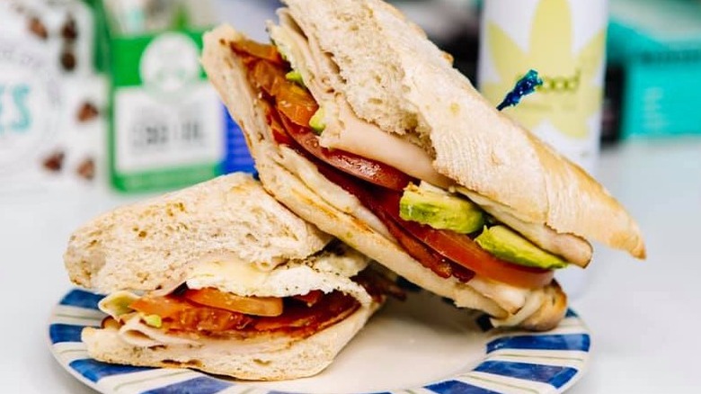Mendez Fuel sandwich on a paper plate in front of a selection of the chain's other food and beverage products