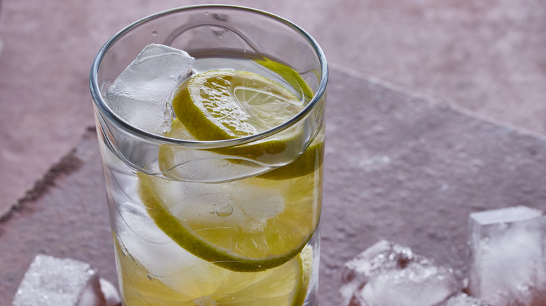 Cocktail of the 1920's gin Rickey served in a tall glass,there is melting ice in the image, shot on a tiled surface.