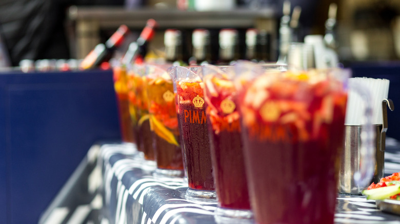 Close up color image depicting clear plastic jugs of Pimm's, the traditional British alcoholic drink, filled with sliced fresh fruit.