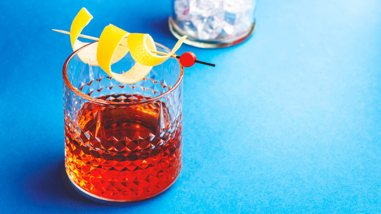 Sazerac, alcoholic cocktail drink with cognac, bourbon, absinthe, bitters, sugar and lemon zest on a blue background
